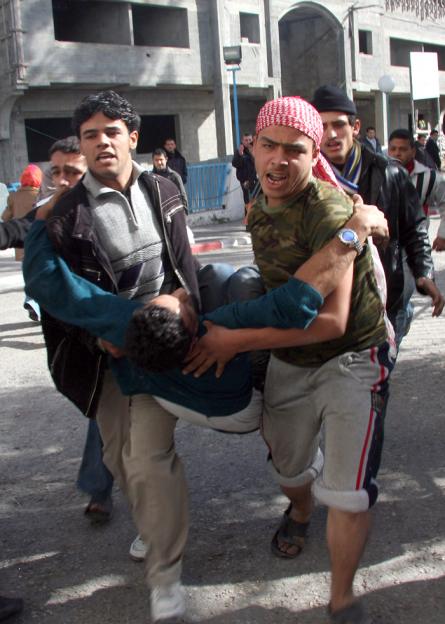 Palestinians in Gaza City carry a victim of the Israeli assault to Al Shifa hospital