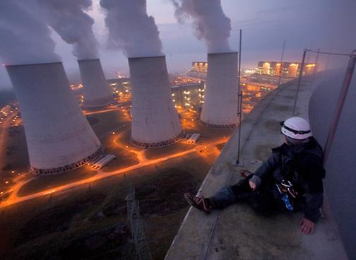 A Greenpeace activists sits at the top of a power plant